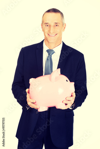 Cheerful businessman holding piggybank