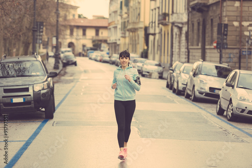 Beautiful young woman jogging alone on city street