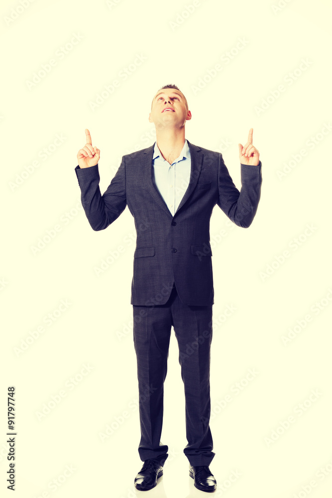 Young businessman pointing upwards Young businessman pointing upwards