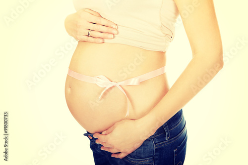 Pregnant woman belly with pink ribbon gift © Piotr Marcinski