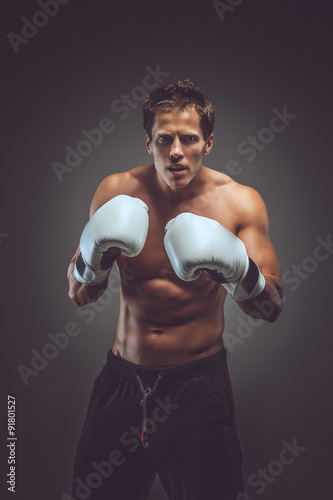 Muscular boxer in white gloves.