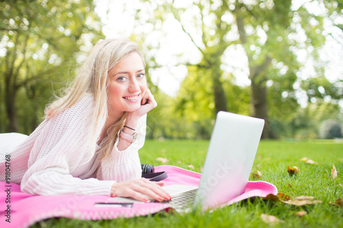 A woman using credit card shopping online with a laptop in the park