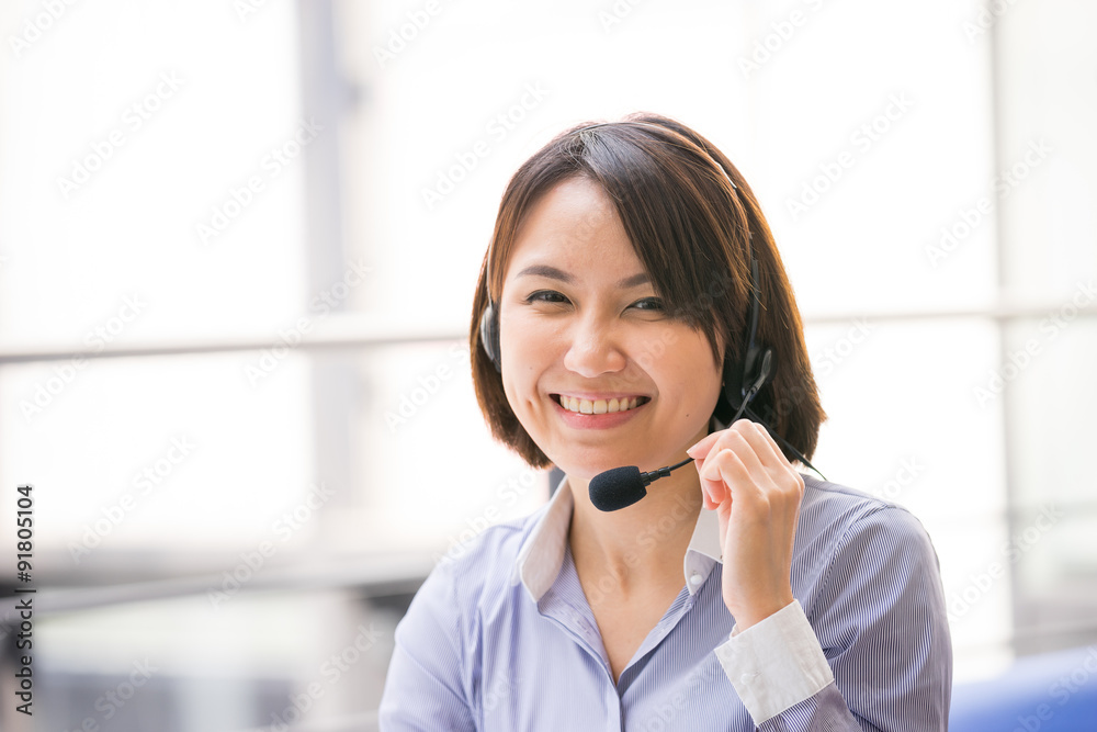 Asian Business woman talking using her headset in the office Asian Business woman talking using her headset in the office