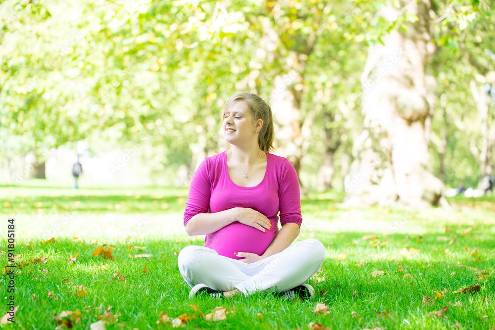 Happy and young pregnant woman in park in summer