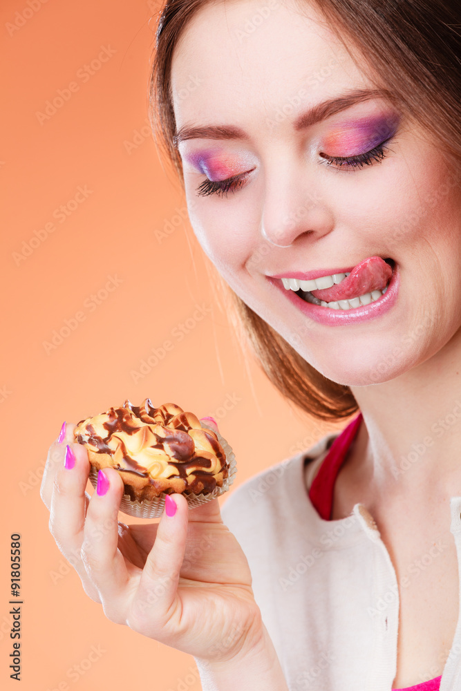 woman holds cake in hand licking lips woman holds cake in hand licking lips