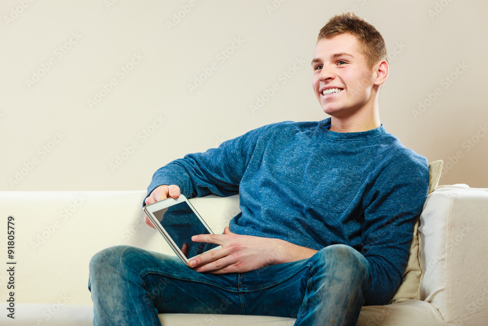 Young man with digital tablet sitting on couch