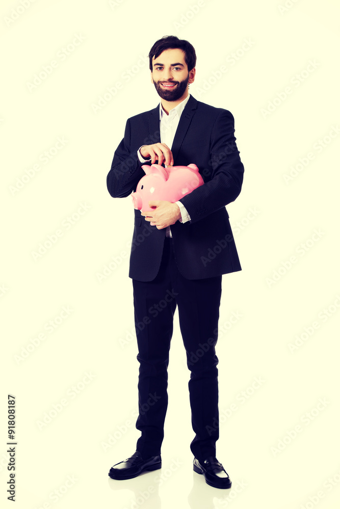 Obraz premium Businessman putting a coin to piggy bank.