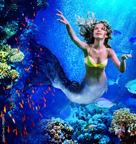 Mermaid dive underwater through coral . photo