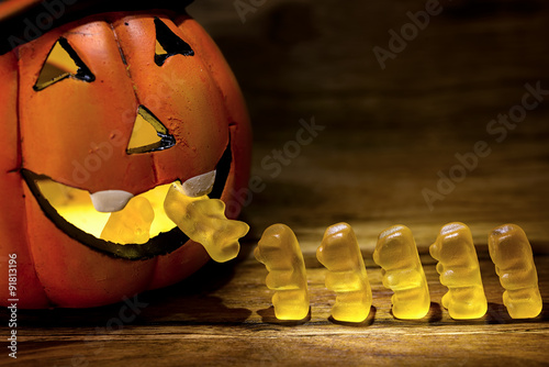 halloween pumpkin eating a row of gummy bear for trick or treat concept