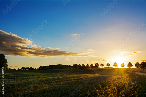 Sunset over a idyllic country landscape with fields and trees
