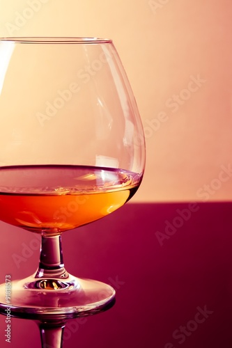 Billede på lærred snifter of brandy in elegant typical cognac glass on purple colored light disco