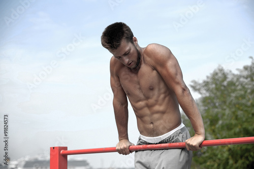 young man exercising on horizontal bar outdoors