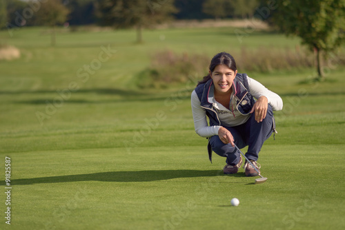 Golferin liest ein Grün vor dem Putten