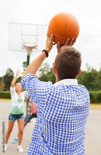 group of happy teenagers playing basketball