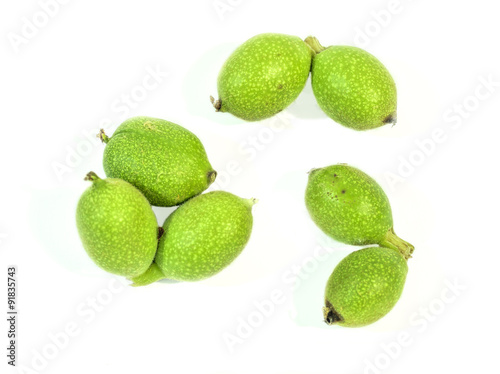 Green seven young walnuts in husks on white background