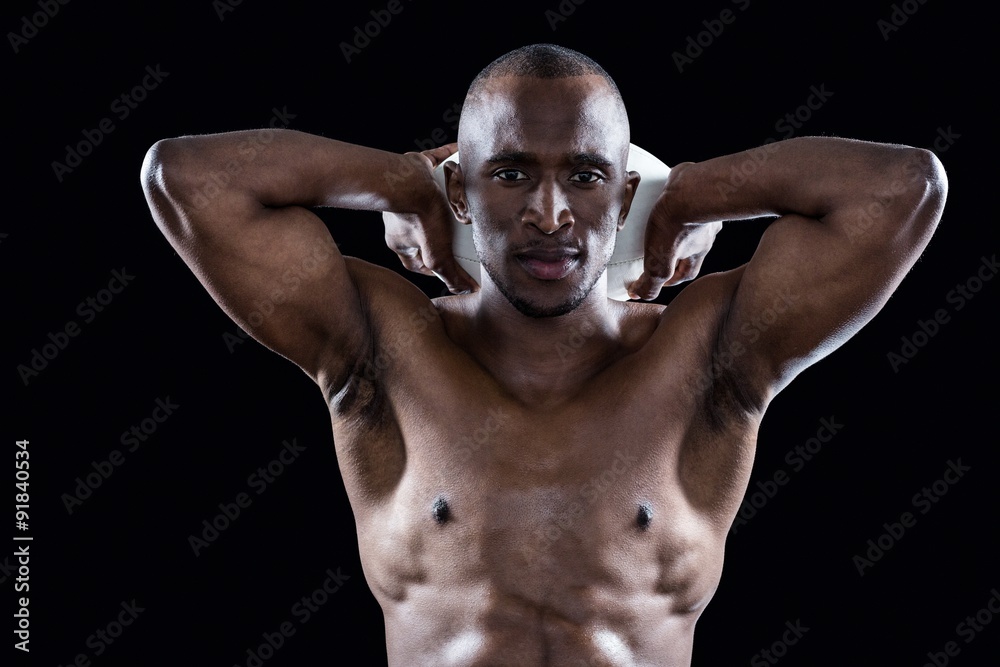 Portrait of shirtless athlete holding rugby ball behind head Portrait of shirtless athlete holding rugby ball behind head
