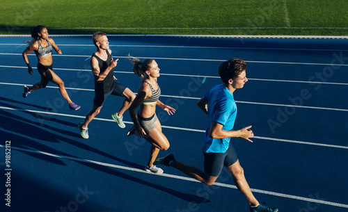 Plakat Multiracial athletes practicing running on racetrack