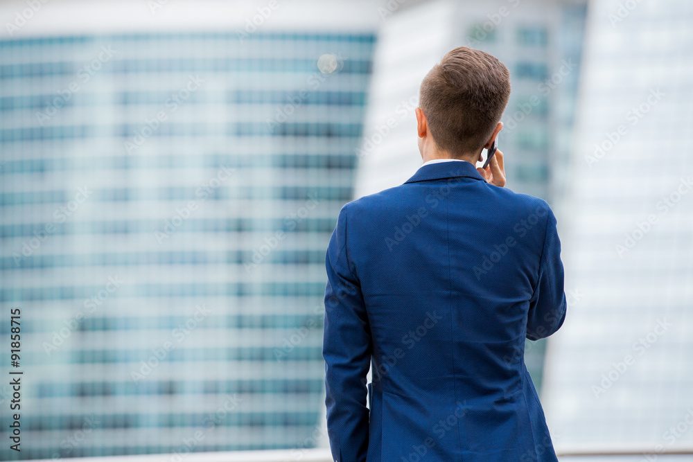 Handsome businessman in suit standing at the street with smart phone in hand. Modern skyscrapers on the background. Handsome businessman in suit standing at the street with smart phone in hand. Modern skyscrapers on the background.