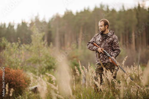 Fototapete Young male hunter in camouflage clothes ready to hunt  with hunt