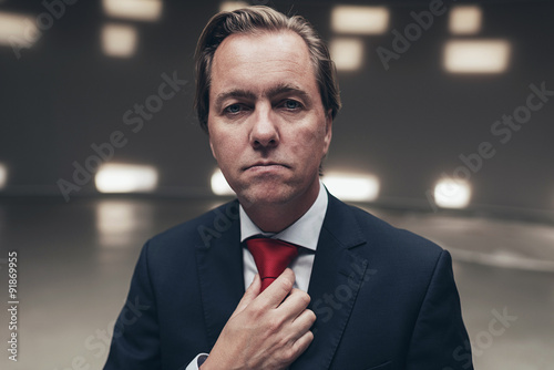 Obraz na plátně Arrogant entrepreneur wearing suit with red tie in empty room.