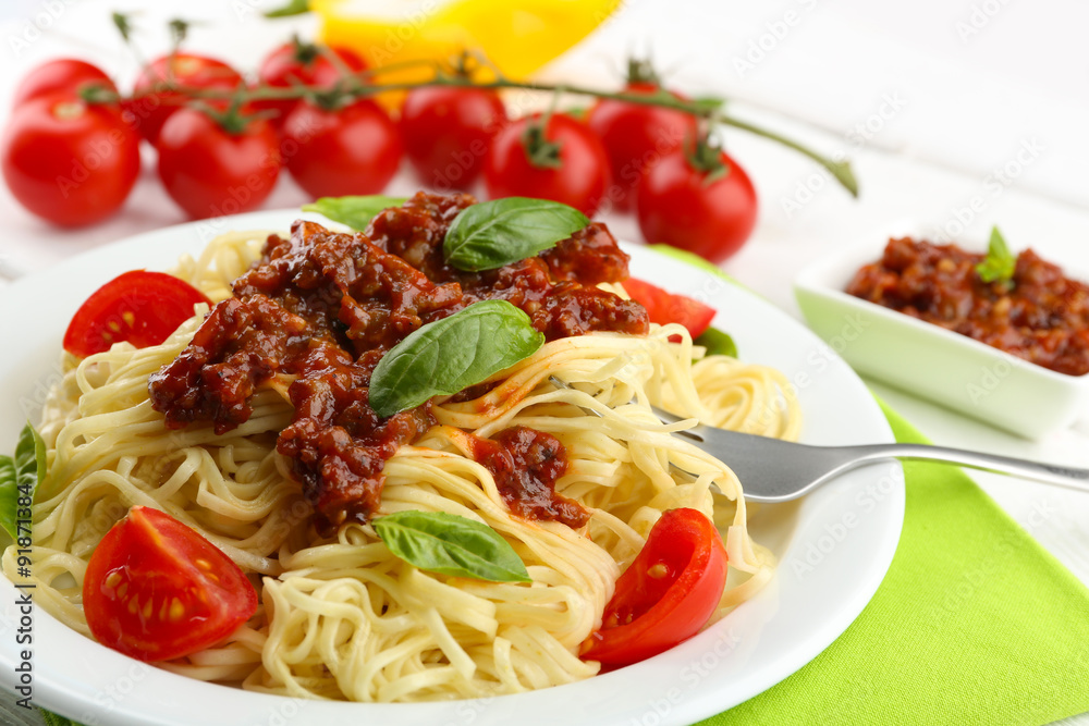 Spaghetti Bolognese on white plate, on color wooden background