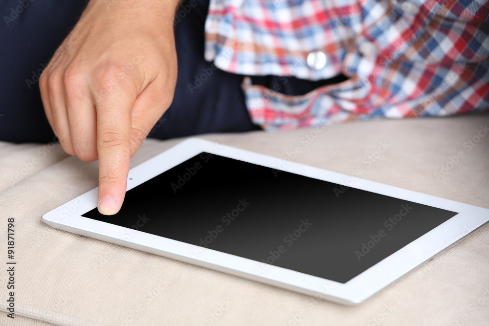 Male hand holding PC tablet on home interior background Male hand holding PC tablet on home interior background