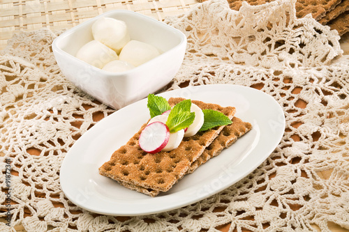 Crispbread with radish, mint and bowl of mozzarella on decorativ photo