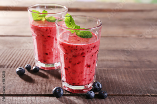Glasses of berry smoothie on wooden background