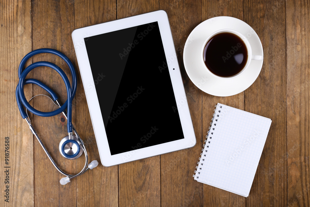 Doctor workplace with blank tablet and stethoscope on wooden background Doctor workplace with blank tablet and stethoscope on wooden background