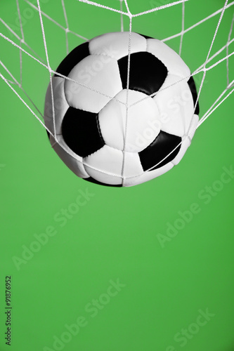 Soccer ball in the net on green background © Africa Studio