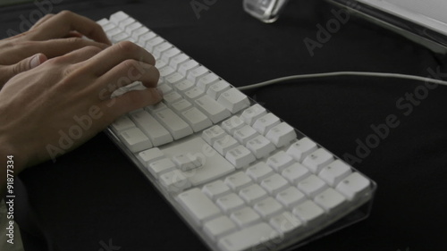Hands type rapidly on a white keyboard.