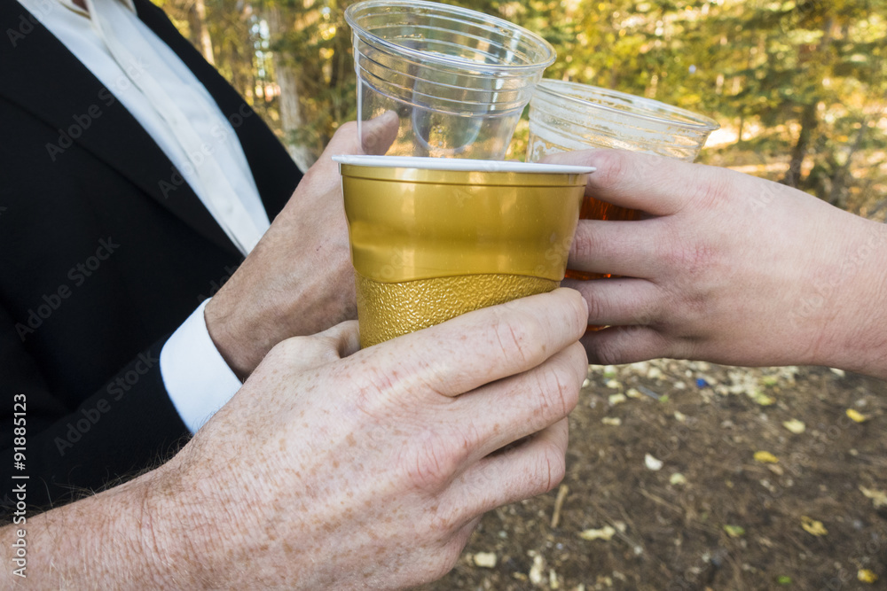 Three men toast their plastic keg cups full of beer  at a party outside