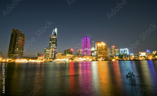 Cityscape of Ho Chi Minh at night with bright illumination of modern architecture, viewed over Saigon river in Southern Vietnam. © danhvc