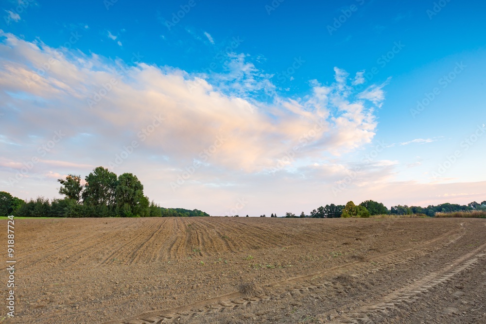 Beautiful plowed field under colorful sunset sky Beautiful plowed field under colorful sunset sky