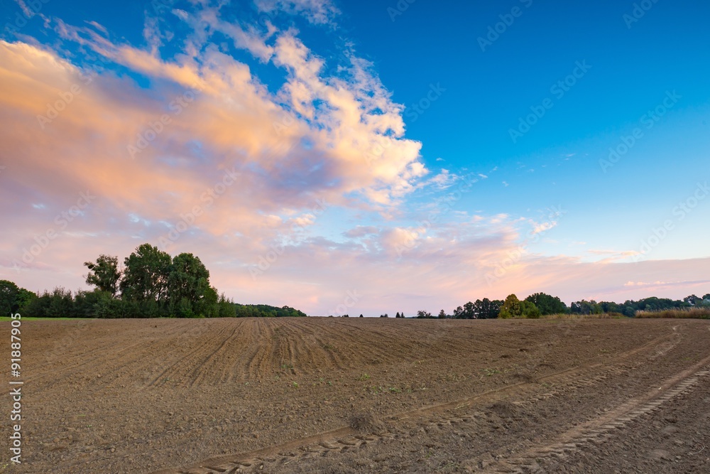 Beautiful plowed field under colorful sunset sky Beautiful plowed field under colorful sunset sky