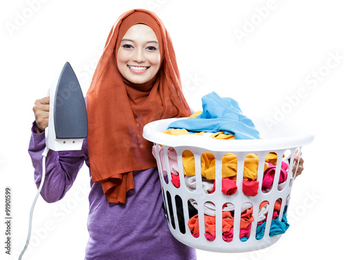 young smiling woman wearing hijab holding iron and carrying laun photo