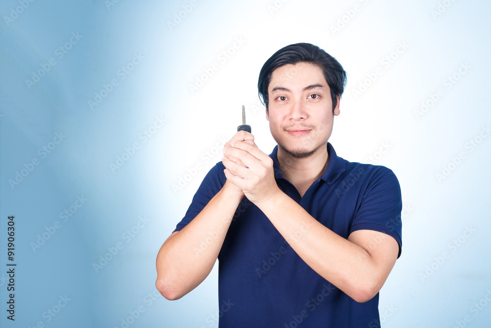 Asian handsome man with the keys of his new car, on blue backgro Asian handsome man with the keys of his new car, on blue backgro