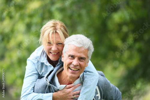 Senior man giving piggyback ride to his wife
