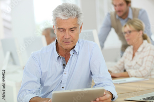 Portrait of senior man working on tablet, training class