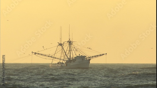 Static shot of a shrimp boat at sea at sunrise