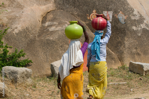 Two Indian women carry water on their heads in  pots  photo