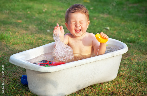 A small happy baby bathed in the bath and playing in a bath