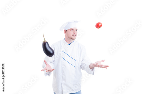 Chef or cook juggling with vegetables an eggpland and tomato photo