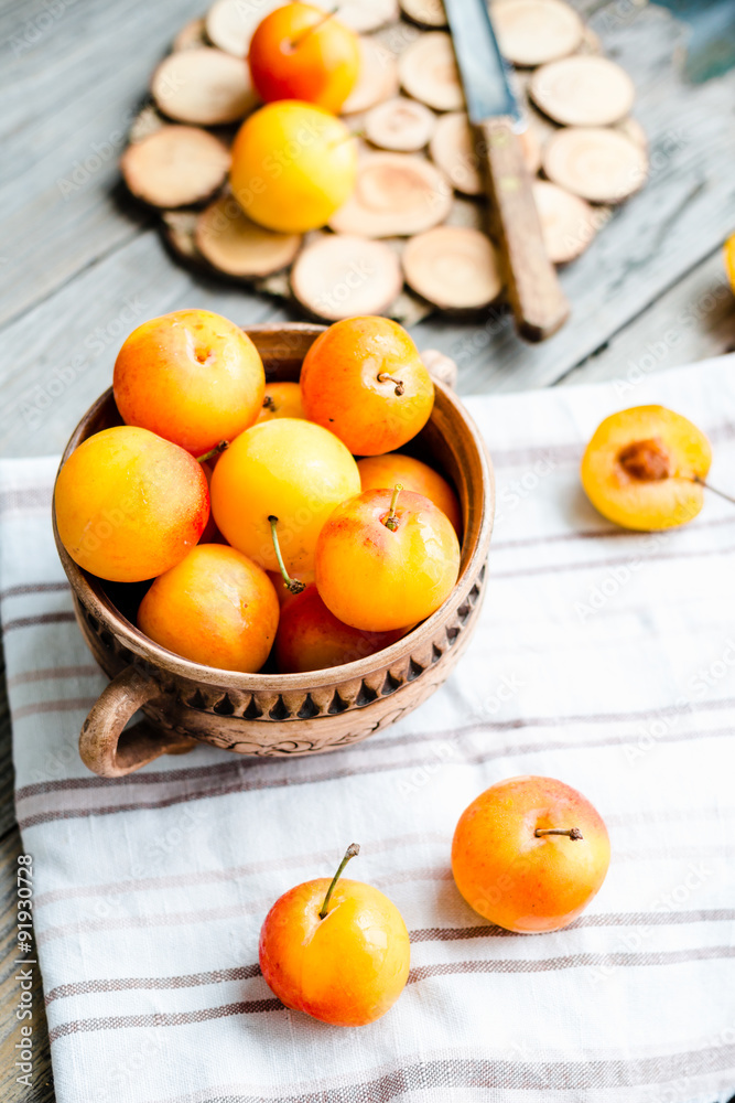 Fresh yellow plums in pottery on gray wooden table, rustic, farm Fresh yellow plums in pottery on gray wooden table, rustic, farm