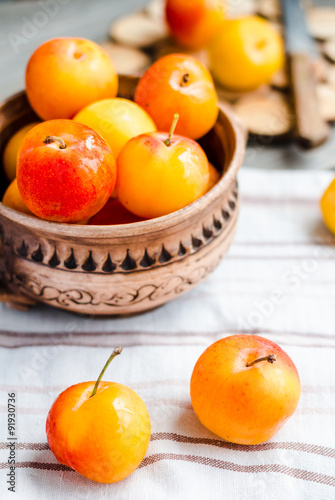 raw plums in pottery on wooden table  rustic  healthy food 