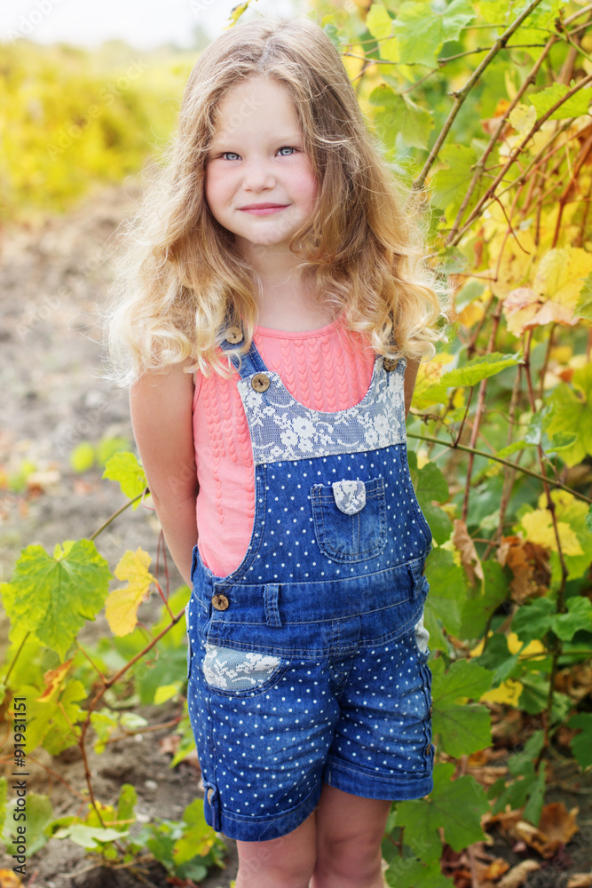 Blonde curly child girl in grape garden Blonde curly child girl in grape garden