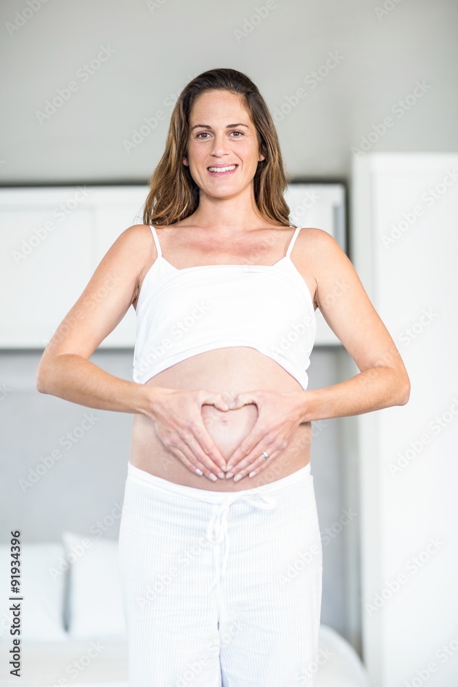 Portrait of happy woman making heart on abdomen Portrait of happy woman making heart on abdomen