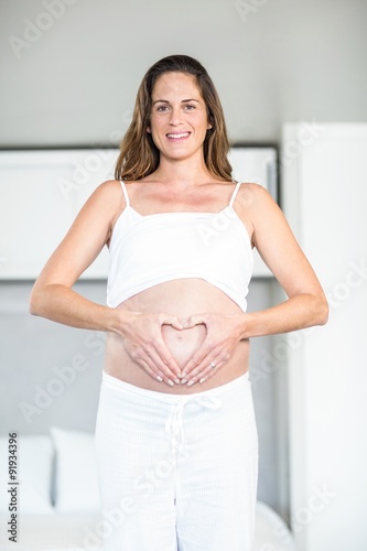 Free Download Portrait of happy woman making heart on abdomen - GFXLoad