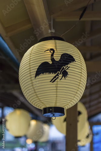 A paper lantern with a cormorant logo on it hanging from the roof of a boat photo