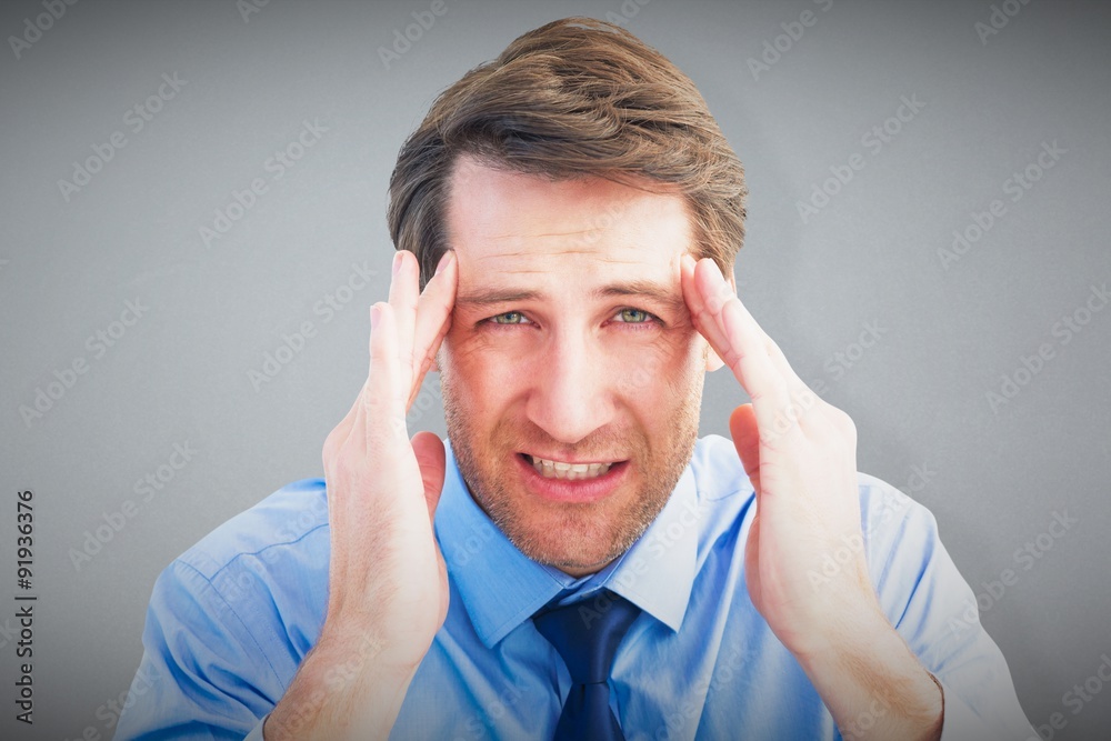 Composite image of young businessman with severe headache Composite image of young businessman with severe headache